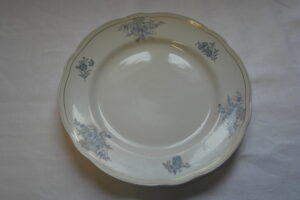 Valkoinen lautanen, jossa sinistä koristekuviota lautasen ulkoreunoissa.