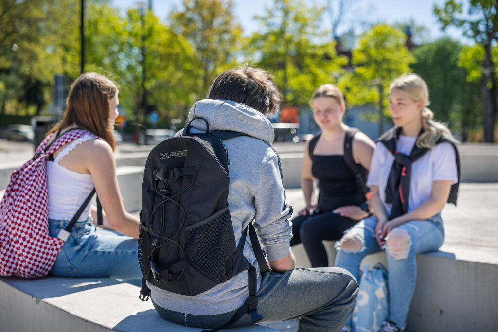 yläkouluikäiset oppilaat istuvat ulkona