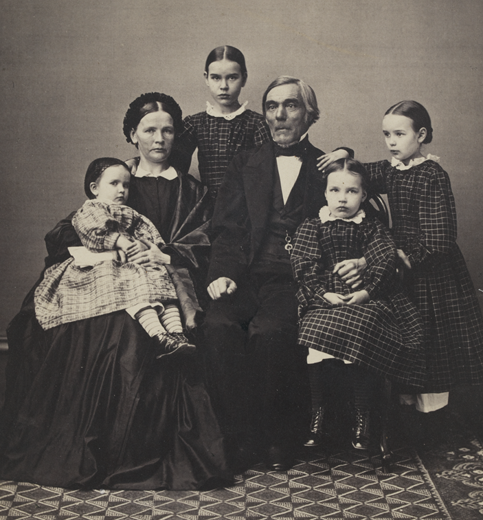 Mustavalkoisessa kuvassa on Elias Lönnrot perheineen. Vasemmalta oikealle kuvassa on Thekla äitinsä Marian sylissä. Vanhempiensa takana seisoo Maria-tytär. Elias istuu Elinan vieressä ja oikeanpuoleisimpana seisoo Ida.